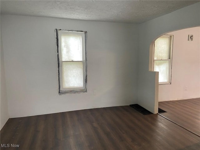 1122 W 17th St, Lorain, OH 44052 - unfurnished room featuring plenty of natural light, arched walkways, wood finished floors, and a textured ceiling