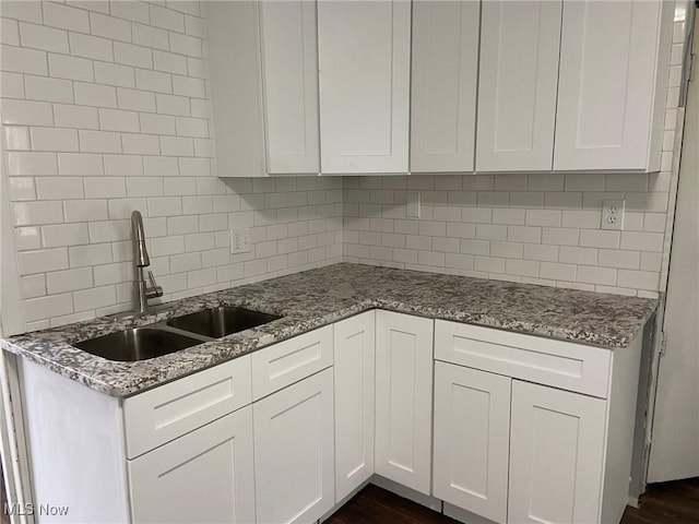 1122 W 17th St, Lorain, OH 44052 - kitchen with backsplash, light stone countertops, white cabinets, and dark wood-style floors