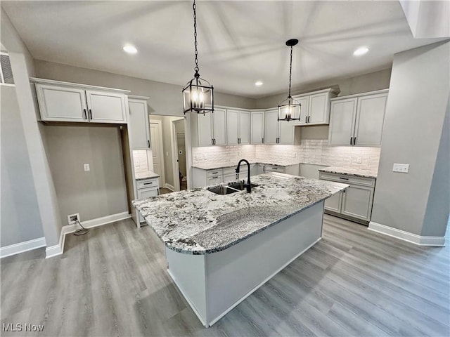 32054 Tuscan Ln Unit L-2, Avon Lake, OH 44012 - kitchen with a center island with sink, light wood finished floors, recessed lighting, backsplash, and light stone countertops
