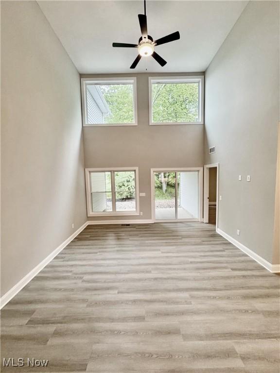 32054 Tuscan Ln Unit L-2, Avon Lake, OH 44012 - unfurnished living room with healthy amount of natural light, wood finished floors, a high ceiling, and a ceiling fan