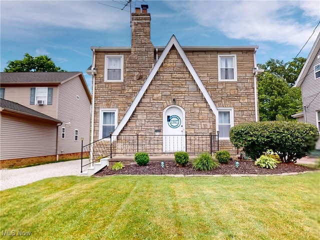 1907 Robindale St, Wickliffe, OH 44092 - tudor-style house with stone siding, a front yard, and a chimney