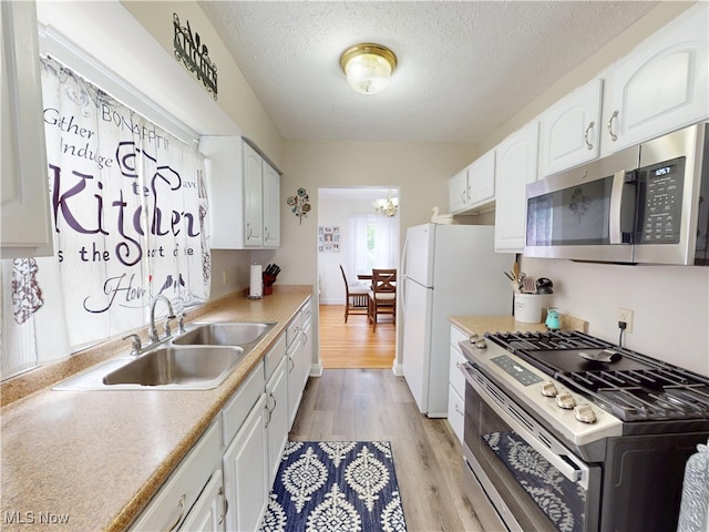 1907 Robindale St, Wickliffe, OH 44092 - kitchen featuring stainless steel appliances, white cabinets, a textured ceiling, light wood finished floors, and a chandelier