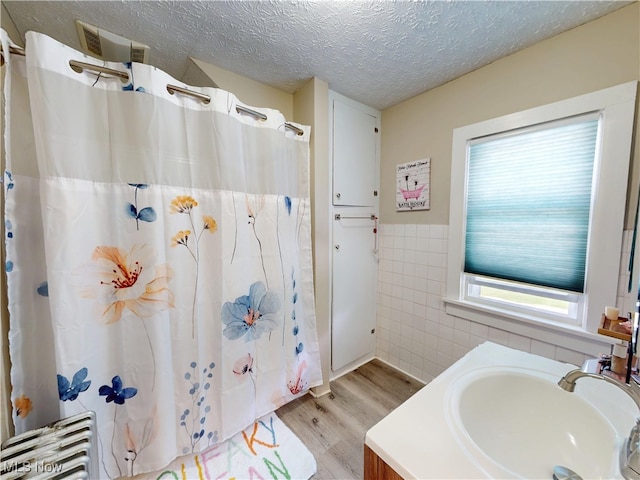 1907 Robindale St, Wickliffe, OH 44092 - full bathroom featuring tile walls, wood finished floors, a wainscoted wall, a shower with shower curtain, and a textured ceiling