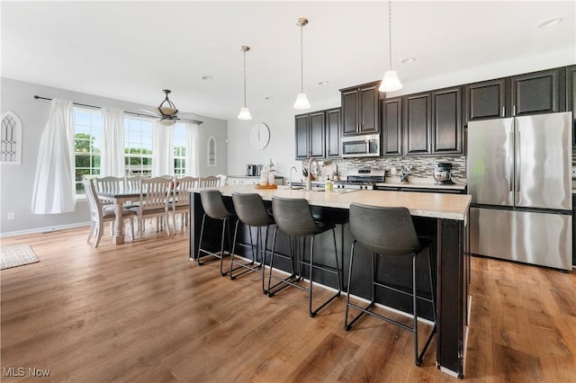 2979 Cloverhurst St NE, Canton, OH 44721 - kitchen featuring appliances with stainless steel finishes, light countertops, a kitchen bar, an island with sink, and tasteful backsplash