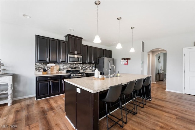 2979 Cloverhurst St NE, Canton, OH 44721 - kitchen with appliances with stainless steel finishes, arched walkways, light countertops, tasteful backsplash, and a center island with sink