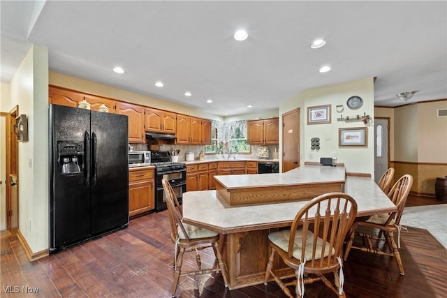 10400 Stoneacre St NW, Canal Fulton, OH 44614 - kitchen featuring black appliances, a peninsula, under cabinet range hood, dark wood-style flooring, and light countertops