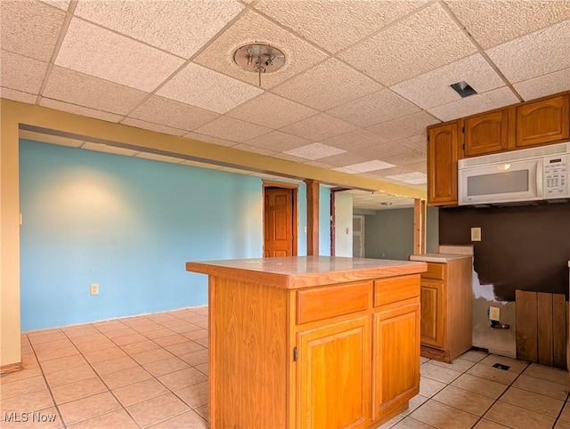 3189 Union Ave SE, Minerva, OH 44657 - kitchen with white microwave, light countertops, a kitchen island, light tile patterned floors, and a drop ceiling