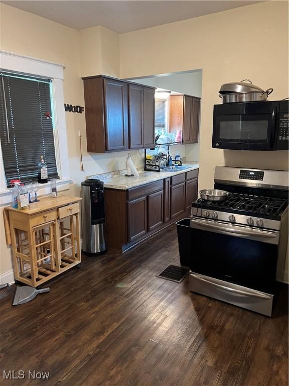 13 Neil St, Niles, OH 44446 - kitchen with black microwave, stainless steel gas range oven, dark wood-style floors, light countertops, and dark brown cabinetry