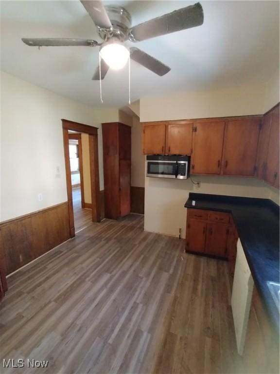207 E Lucius Ave, Youngstown, OH 44507 - kitchen with stainless steel microwave, brown cabinetry, wood finished floors, a ceiling fan, and wainscoting