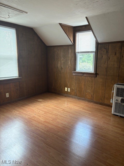 206 Fowler, Cortland, OH 44410 - bonus room with light wood-style floors, wooden walls, vaulted ceiling, heating unit, and a textured ceiling