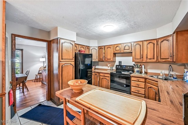 1683 Ridgewood Dr, Salem, OH 44460 - kitchen with black appliances, light countertops, brown cabinetry, light tile patterned flooring, and a textured ceiling