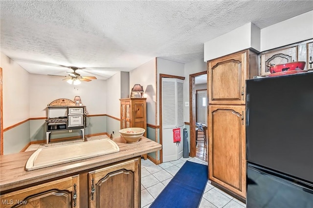 1683 Ridgewood Dr, Salem, OH 44460 - kitchen featuring freestanding refrigerator, ceiling fan, light tile patterned floors, a textured ceiling, and brown cabinets