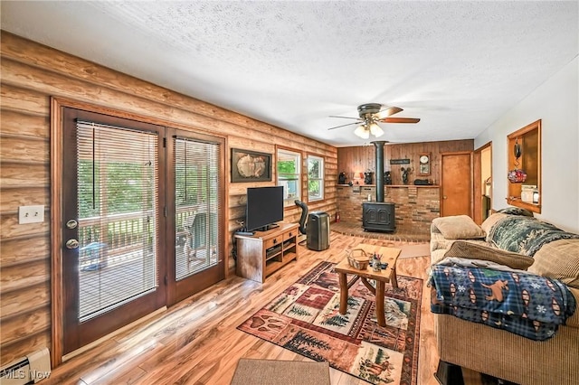 1683 Ridgewood Dr, Salem, OH 44460 - living room featuring a wood stove, rustic walls, wood finished floors, a textured ceiling, and ceiling fan
