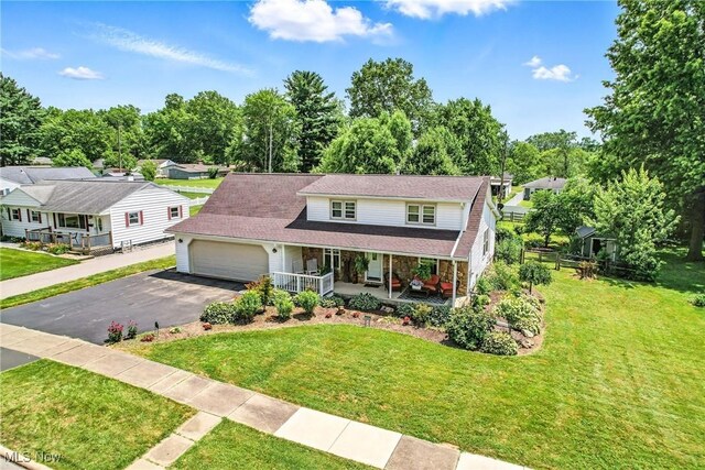 1683 Ridgewood Dr, Salem, OH 44460 - view of front of house with covered porch, asphalt driveway, an attached garage, and a front lawn