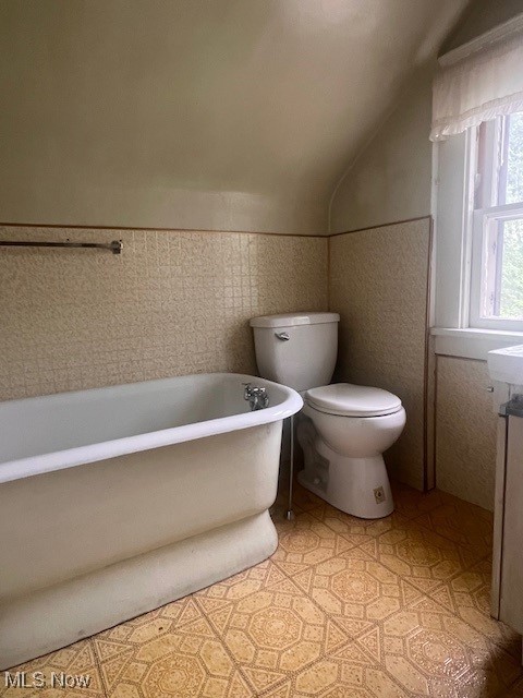 1767 Northfield, Warren, OH 44485 - bathroom featuring a soaking tub, lofted ceiling, vanity, and a wainscoted wall