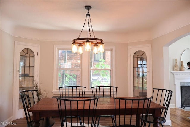 3781 Washington Blvd, University Heights, OH 44118 - dining area with arched walkways, a fireplace with flush hearth, wood finished floors, and a chandelier