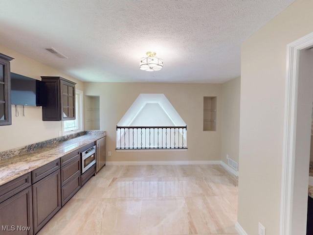 2474 Ginger Wren Rd, Pepper Pike, OH 44124 - kitchen featuring glass insert cabinets, a textured ceiling, stainless steel microwave, and light stone countertops