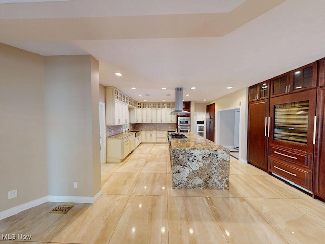 2474 Ginger Wren Rd, Pepper Pike, OH 44124 - kitchen featuring island range hood, light stone countertops, backsplash, glass insert cabinets, and a center island