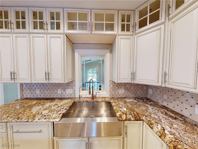 2474 Ginger Wren Rd, Pepper Pike, OH 44124 - kitchen featuring light stone counters, glass insert cabinets, tasteful backsplash, and white cabinets