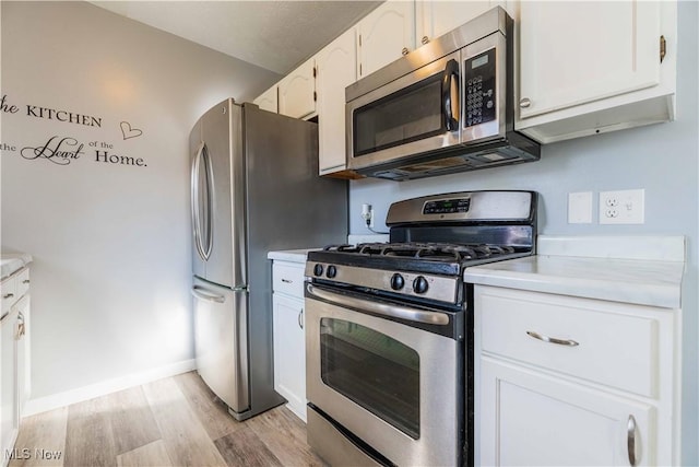 1582 Hilda Ave, Lakemore, OH 44250 - kitchen featuring stainless steel appliances, light wood-type flooring, light countertops, and white cabinetry