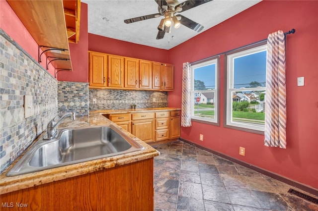 3303 Tuxedo Ave, Parma, OH 44134 - kitchen with backsplash, light countertops, ceiling fan, brown cabinets, and stone tile flooring