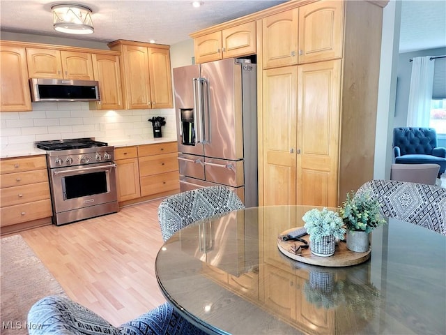 2977 Pirates Cv, Aurora, OH 44202 - kitchen with premium appliances, light brown cabinetry, light wood-style flooring, and a textured ceiling
