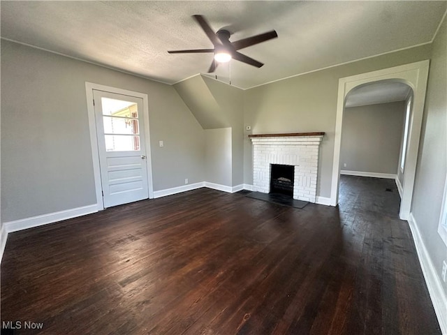 16707 Terrace Ave, Caldwell, OH 43724 - unfurnished living room featuring a ceiling fan, arched walkways, dark wood finished floors, and a brick fireplace