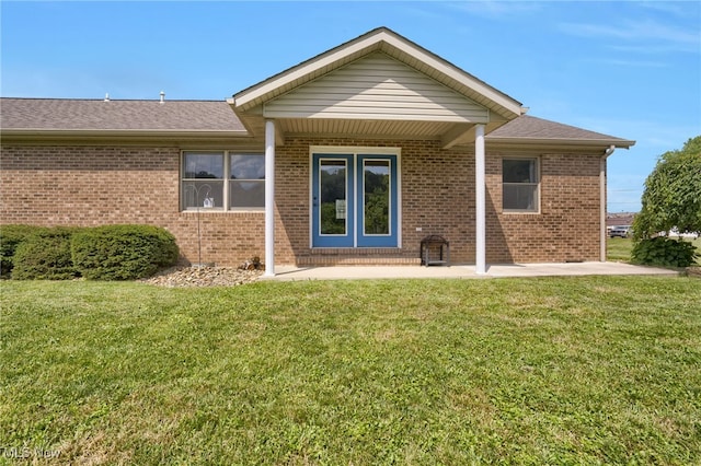 45330 Maple View Cir, Caldwell, OH 43724 - view of exterior entry featuring brick siding, a lawn, a shingled roof, and a patio