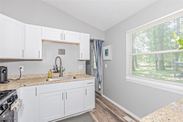 3498 Clayton Dr, North Olmsted, OH 44070 - kitchen featuring gas stove, vaulted ceiling, light wood finished floors, white cabinets, and light stone counters