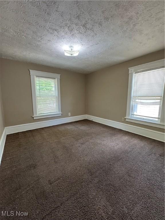 2239 23rd St SW, Akron, OH 44314 - unfurnished room with a textured ceiling and dark colored carpet