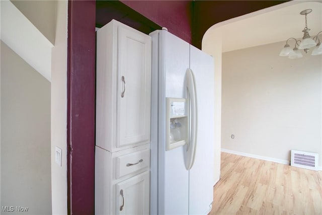 4606 Maplecrest Ave, Parma, OH 44134 - kitchen featuring a chandelier, light wood-style floors, white fridge with ice dispenser, pendant lighting, and white cabinets