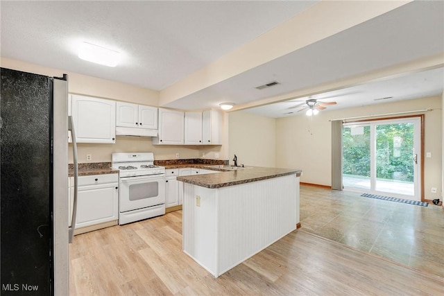 11253 Hampton Bay Ln, Concord, OH 44077 - kitchen with freestanding refrigerator, white range with gas cooktop, a peninsula, dark countertops, and under cabinet range hood