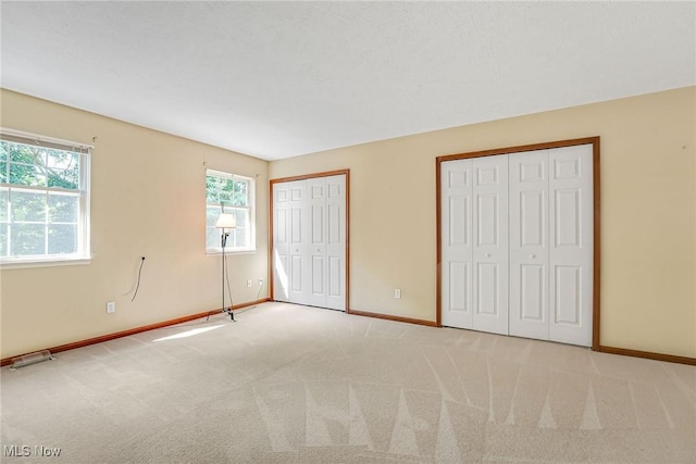 11253 Hampton Bay Ln, Concord, OH 44077 - unfurnished bedroom featuring two closets, multiple windows, and light carpet