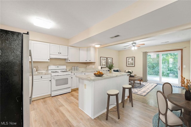 11253 Hampton Bay Ln, Concord, OH 44077 - kitchen with freestanding refrigerator, white gas range, under cabinet range hood, white cabinetry, and light wood-style floors