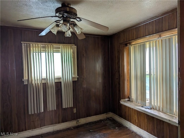 14717 Orinoco Ave, East Cleveland, OH 44112 - empty room featuring dark wood-style flooring, a ceiling fan, a textured ceiling, and wood walls