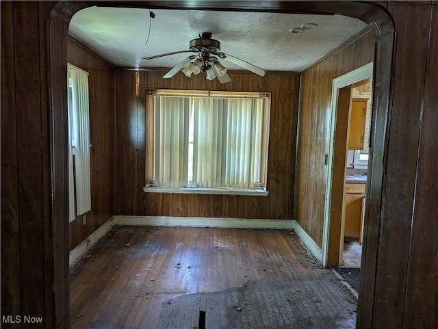 14717 Orinoco Ave, East Cleveland, OH 44112 - unfurnished room with arched walkways, wood-type flooring, ceiling fan, and wood walls