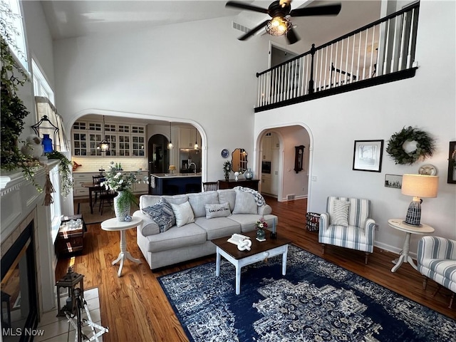 660 Rustic Knoll Dr, Kent, OH 44240 - living area with arched walkways, high vaulted ceiling, ceiling fan, wood finished floors, and a glass covered fireplace