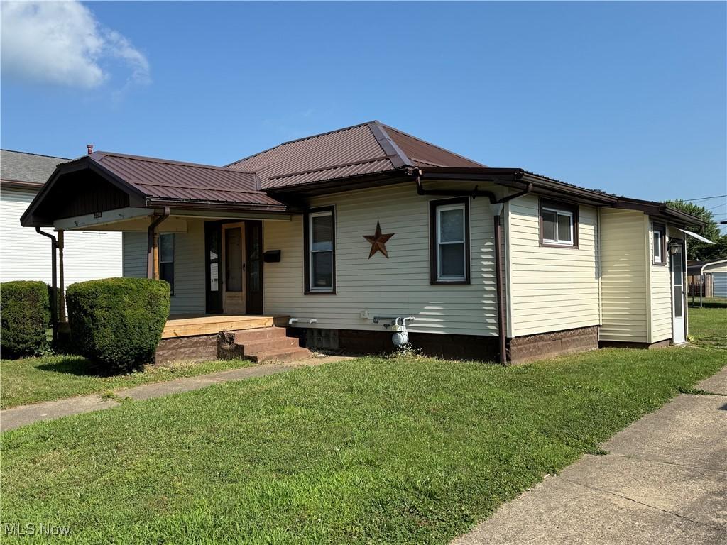 204 E 4th St, West Lafayette, OH 43845 - view of front facade with a front lawn, a metal roof, and covered porch