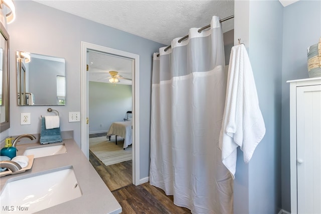 1648 E Turkey Run Dr, Newark, OH 43055 - bathroom featuring wood finished floors, double vanity, a ceiling fan, a shower with curtain, and a textured ceiling