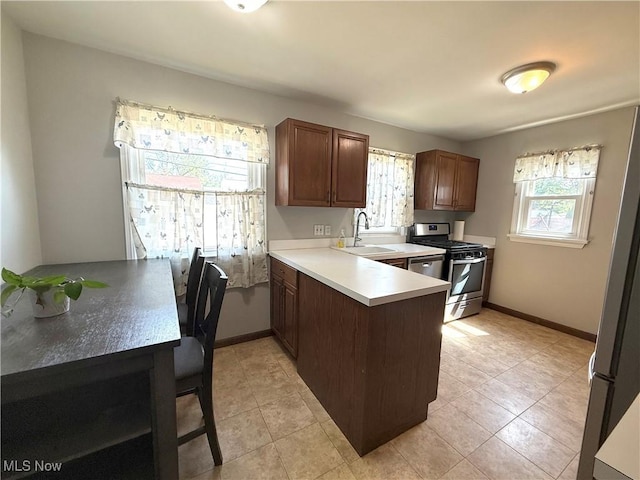 21571 Ball Ave, Euclid, OH 44123 - kitchen featuring stainless steel appliances, a peninsula, light countertops, and light tile patterned flooring
