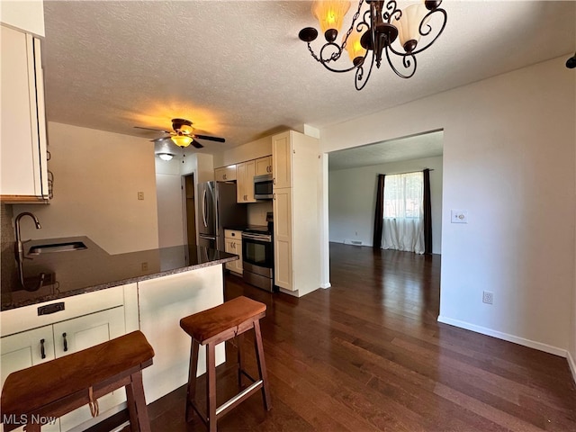 35049 N Turtle Trl Unit C, Willoughby, OH 44094 - kitchen featuring appliances with stainless steel finishes, dark wood-style flooring, dark countertops, a peninsula, and a textured ceiling