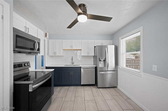 1835 Rockefeller Rd, Wickliffe, OH 44092 - kitchen with stainless steel appliances, light countertops, white cabinetry, decorative backsplash, and wainscoting