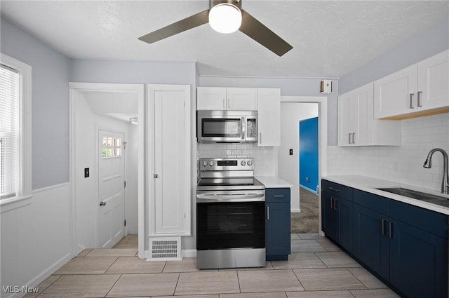 1835 Rockefeller Rd, Wickliffe, OH 44092 - kitchen featuring stainless steel appliances, blue cabinetry, white cabinets, light countertops, and a textured ceiling