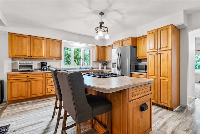 6170 Oberlin Rd, Amherst, OH 44001 - kitchen with stainless steel appliances, a center island, brown cabinetry, and a breakfast bar area