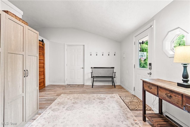 6170 Oberlin Rd, Amherst, OH 44001 - bedroom featuring vaulted ceiling, light wood-style flooring, and a barn door