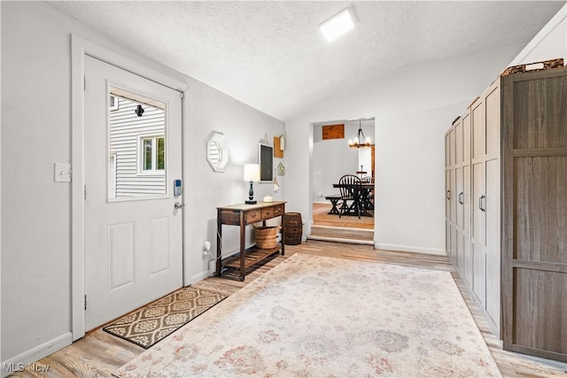 6170 Oberlin Rd, Amherst, OH 44001 - foyer entrance with light wood-type flooring, a textured ceiling, a chandelier, and lofted ceiling