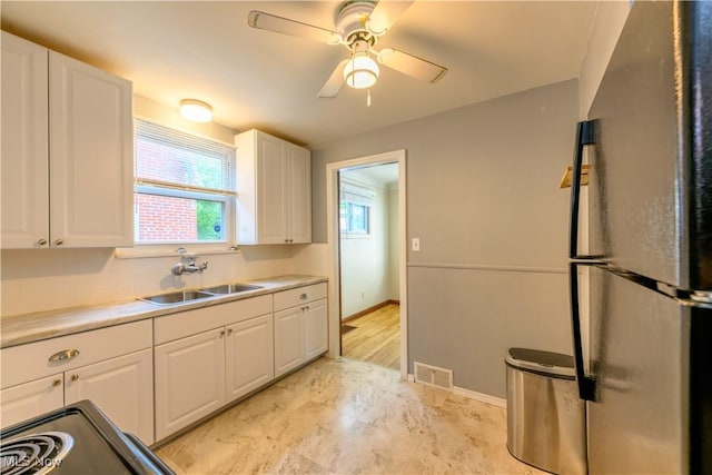 19005 Pawnee Ave, Cleveland, OH 44119 - kitchen with freestanding refrigerator, white cabinets, ceiling fan, light countertops, and light marble finish floors