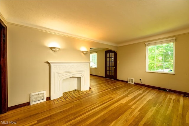 19005 Pawnee Ave, Cleveland, OH 44119 - unfurnished living room featuring arched walkways, hardwood / wood-style floors, a fireplace with flush hearth, and crown molding