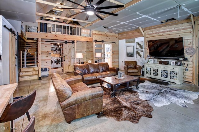 10770 W W Salem Rd, West Salem, OH 44287 - living room with a barn door, finished concrete flooring, washing machine and dryer, a ceiling fan, and wood walls