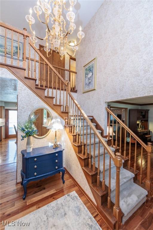 6252 Pebblebrook Ln, North Olmsted, OH 44070 - stairway with wallpapered walls, a towering ceiling, wood finished floors, and a chandelier